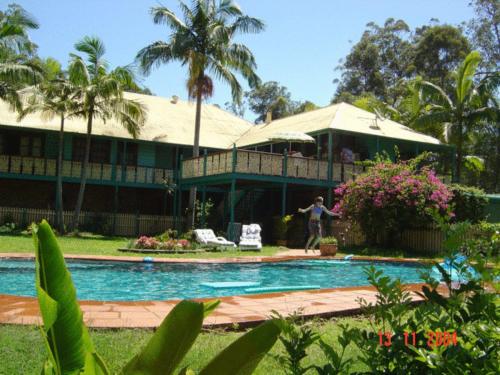a man standing in front of a house with a swimming pool at Riviera Bed & Breakfast in Gold Coast