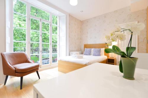 um quarto com uma cama, uma cadeira e uma janela em Paddington Green Serviced Apartments by Concept Apartments em Londres