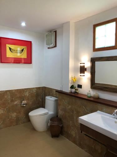 a bathroom with a toilet and a sink and a mirror at On The Mekong Resort in Luang Prabang