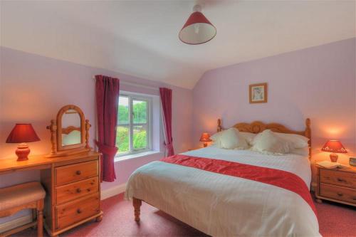 a bedroom with a bed and a dresser and a mirror at Moonfleet Cottage in Charmouth