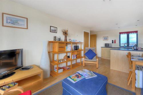 a living room with a blue couch and a kitchen at 8 Driftwood in West Bay