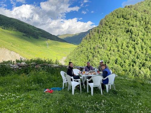 a group of people sitting at a table in the grass at Gunter Guest house in Adishi