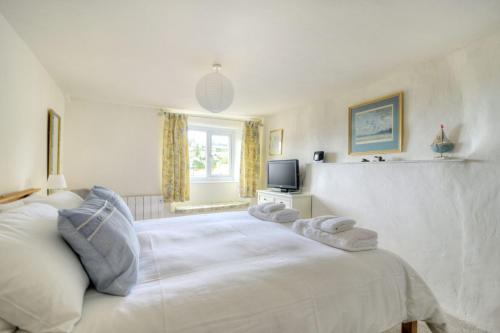 a bedroom with a white bed with towels on it at Smugglers Cottage in Beer