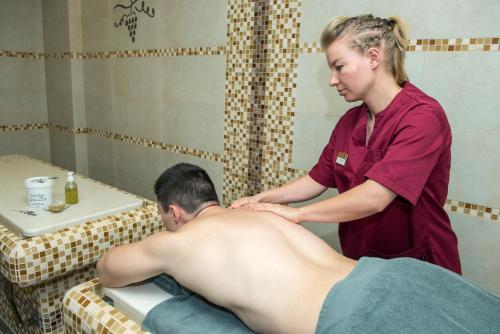 a woman giving a man a massage in a bathroom at Uva Nestum Wine & SPA in Gotse Delchev