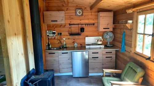 uma cozinha num chalé de madeira com um frigorífico em Domek nad jeziorem Gowidlińskim em Podiazy