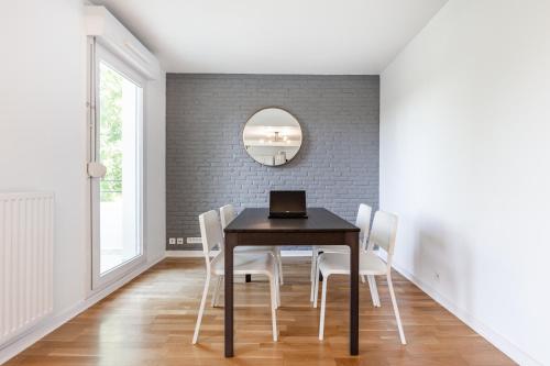 a dining room table with white chairs and a laptop on it at Design 3 bedrooms appartment, near Champs Elysees in Nanterre