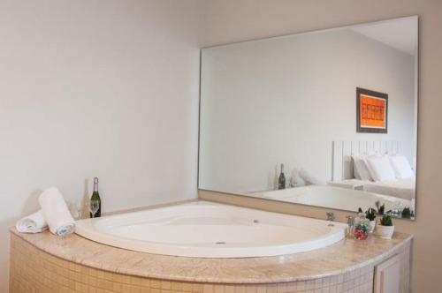 a bath tub with a large mirror in a bathroom at Hotel Portal Premium in Brumado