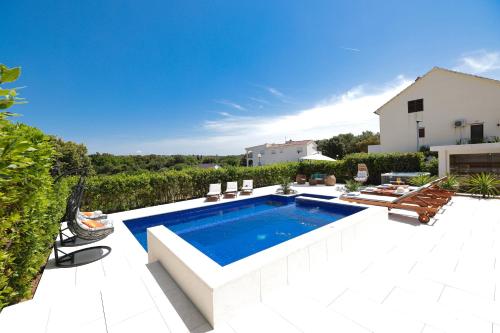 a swimming pool in a yard with chairs and a house at Villa Pino with Pool, Sauna & Jacuzzi in Petrcane