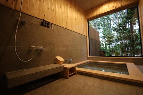 łazienka z wanną i dużym oknem w obiekcie SAUNAFORESTCABIN軽井沢御代田zenasobi棟 w mieście Oiwake