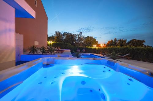 a hot tub in the backyard of a house at night at Villa Pino with Pool, Sauna & Jacuzzi in Petrcane