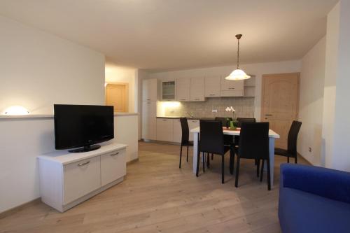 a living room and kitchen with a table and a television at Varesco Appartamenti in Carano