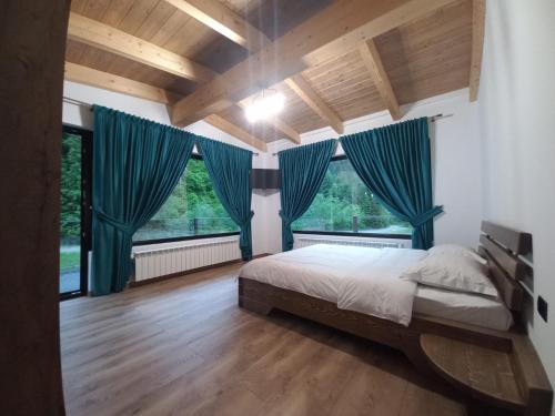1 dormitorio con cortinas azules y 1 cama grande en CABANA NEMTUCU, en Borşa