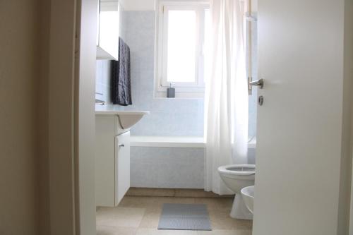 łazienka z wanną, toaletą i oknem w obiekcie Cozy apartment with Free Parking & close to Lake w mieście Lugano