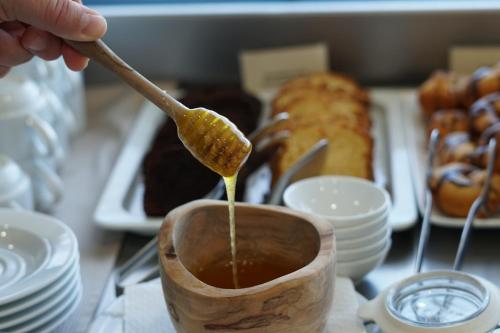a person is pouring honey into a cup of coffee at Uva Nestum Wine & SPA in Gotse Delchev