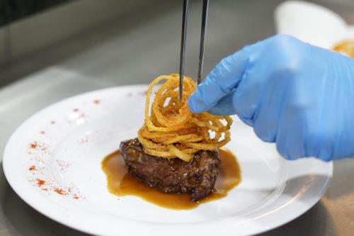 a person in blue gloves holding a piece of food on a plate at Uva Nestum Wine & SPA in Gotse Delchev