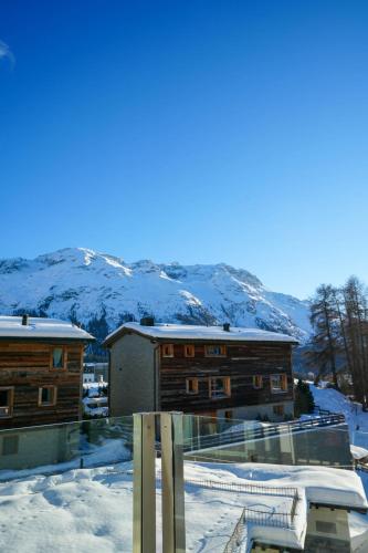 a building in the snow with mountains in the background at Hotel Bären in St. Moritz