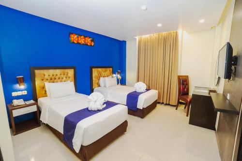 a hotel room with two beds and a blue wall at Parkside Star Hotel Jayapura in Jayapura