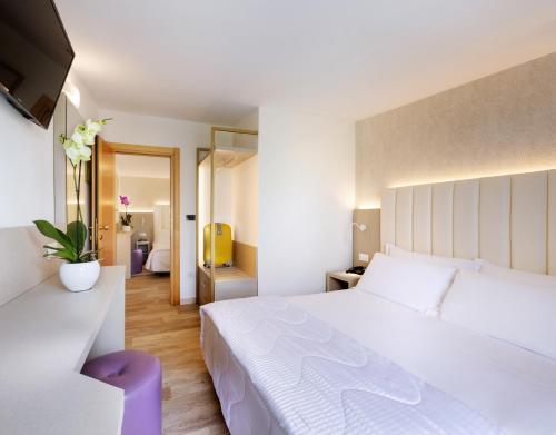 a bedroom with a large white bed with a purple stool at Hotel Castellucci in Bellaria-Igea Marina