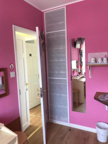 um quarto rosa com uma porta de vidro com um espelho em Becontreelodge em Dagenham