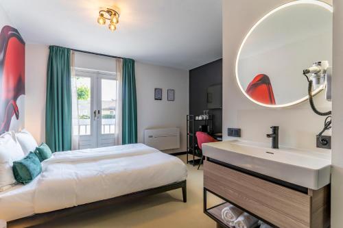 a bedroom with a bed and a sink and a mirror at Dormio Wijnhotel Valkenburg in Valkenburg