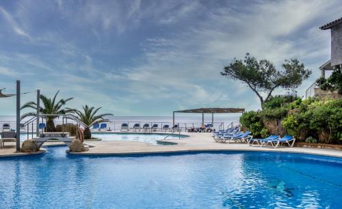 una piscina en un complejo con sillas y mesas en Eden Roc Hotel & Spa by Brava Hoteles, en Sant Feliu de Guíxols