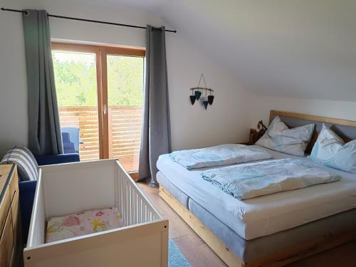 um quarto com uma cama, um berço e uma janela em Ferienwohnung Fabiella em Millstatt