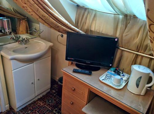 un monitor di computer appoggiato su una scrivania in un bagno di Acorn Guest House a Cambridge