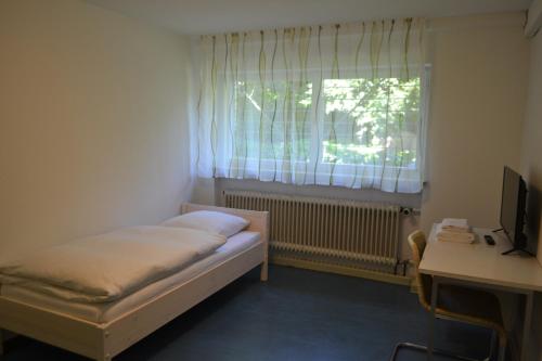 a small room with a bed and a desk and a window at Monteurenwohnung im Untergeschoss mit Tageslicht in Bad Urach