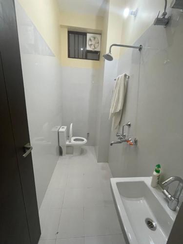 a white bathroom with a toilet and a sink at BLD Restaurant And Home Stay in Dehradun