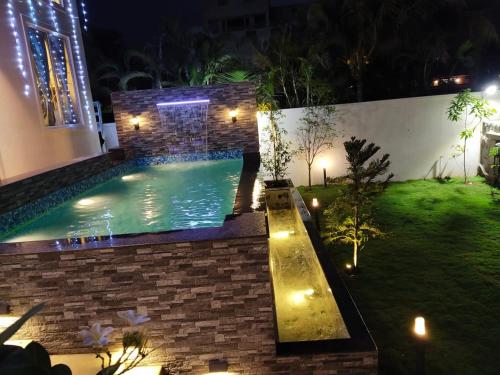 a backyard with a swimming pool at night at Mer Vue Villa, Kovalam, ECR, Chennai in Chennai