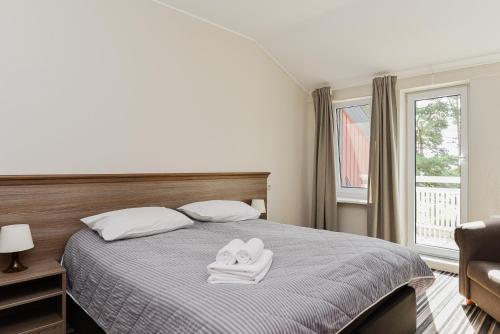 a bedroom with a bed with two towels on it at Skalva Nida in Nida