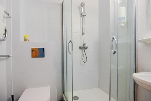 a bathroom with a shower and a toilet and a sink at Skalva Nida in Nida