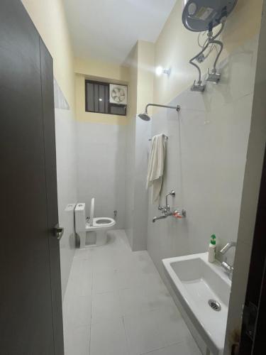 a white bathroom with a sink and a toilet at BLD Restaurant And Home Stay in Dehradun