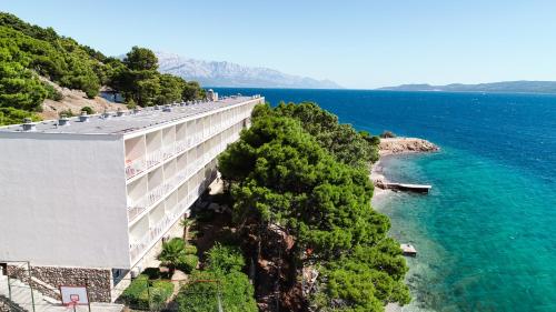 a building on the side of a mountain next to the water at Holiday Village Sagitta - Light All Inclusive in Omiš