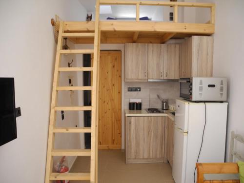 uma cama alta numa pequena cozinha com um frigorífico em Xerolithia em Éxo Goniá