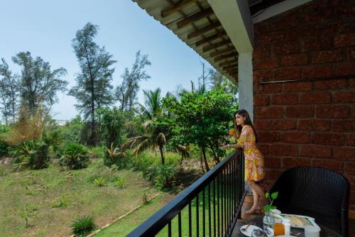 a woman standing on the balcony of a house at Lotus an Eco Beach Resort Dapoli Murud in Dapoli