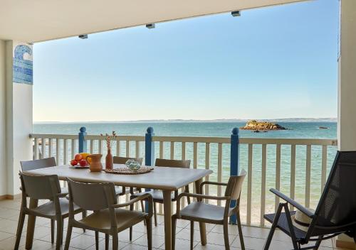 a table and chairs on a balcony with the ocean at Résidence Pierre & Vacances Premium Le Coteau et la Mer in Tréboul