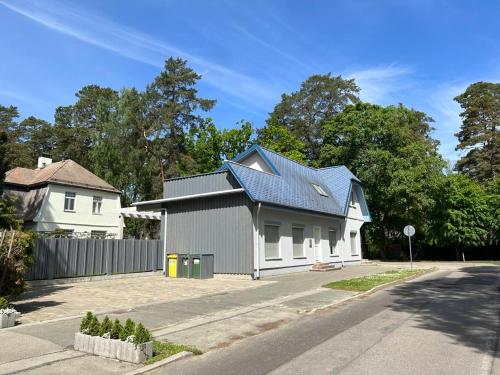 a white house with a gray roof on a street at Cozy beach house Jurmala in Jūrmala