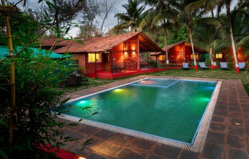 a swimming pool in front of a house at Lotus an Eco Beach Resort Dapoli Murud in Dapoli