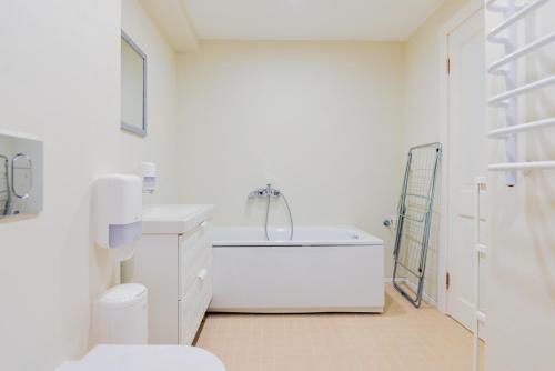 a white bathroom with a tub and a toilet at Skalva Nida in Nida