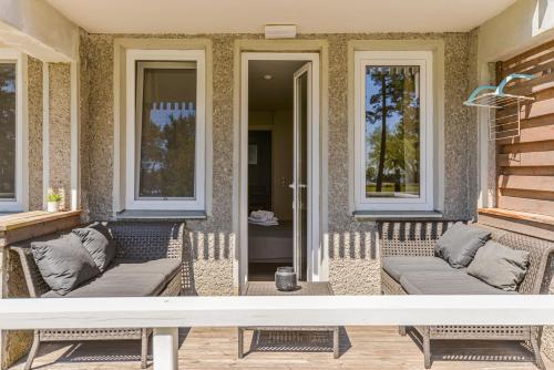 a patio with two couches and two windows at Skalva Nida in Nida