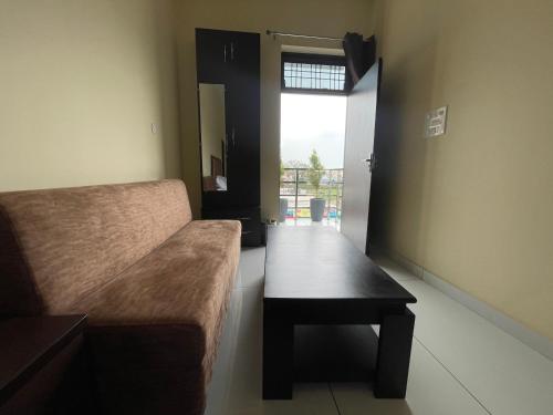 Zimmer mit Sofa, Tisch und Fenster in der Unterkunft BLD Restaurant And Home Stay in Dehradun