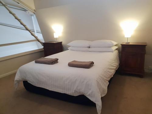 a bedroom with a large white bed with two pillows at Granita's - 2 bedroom converted South Fremantle warehouse apartment in Fremantle