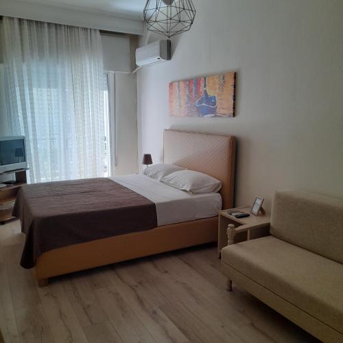 a bedroom with a bed and a couch and a window at Zefi's Apartment in Nea Peramos
