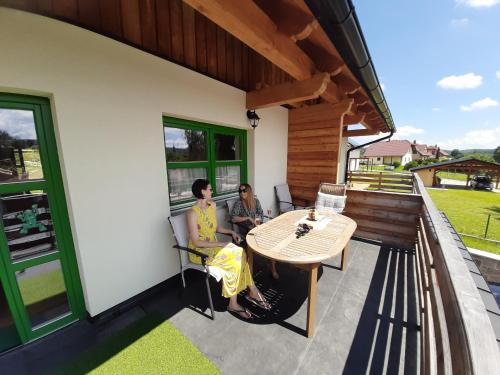 two people sitting on the porch of a house at Zelený Jelen - horský apartmán in Stachy