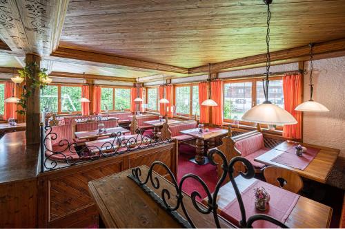 a dining room with tables and chairs and windows at Wohlfühlhotel Frohsinn in Fischen
