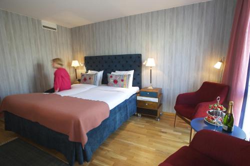 a hotel room with a bed and a person in a chair at Best Western Plus Hotel Noble House in Malmö
