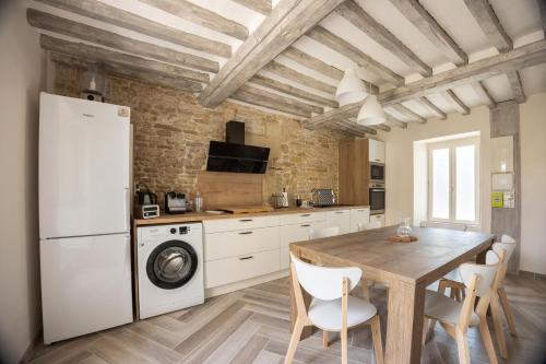 une cuisine avec une table et un réfrigérateur blanc dans l'établissement Maison de la Mer - A Lagrune-sur-Mer, à Langrune-sur-Mer