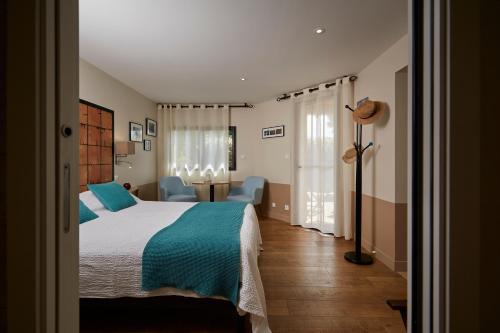 a bedroom with a large bed with blue sheets and blue chairs at Salamandre et Hippocampe in Lanton