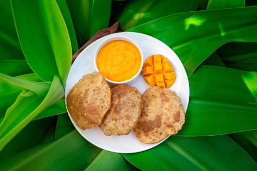 a plate with three biscuits and a bowl of orange dip at Lotus an Eco Beach Resort Dapoli Murud in Dapoli